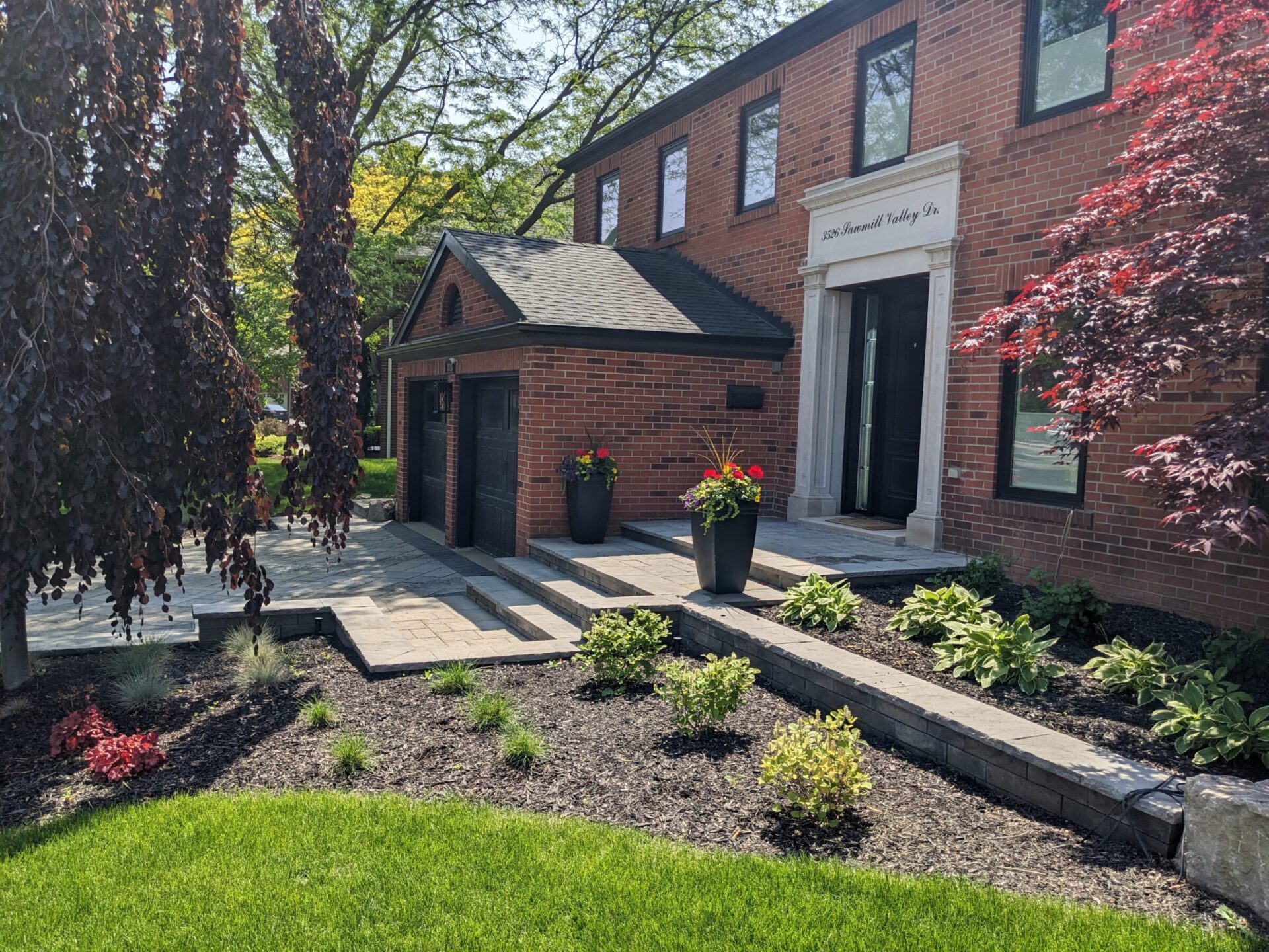 This image shows a well-manicured garden in front of a brick building with a black door and sign reading "800 Hundred Valley Inn."