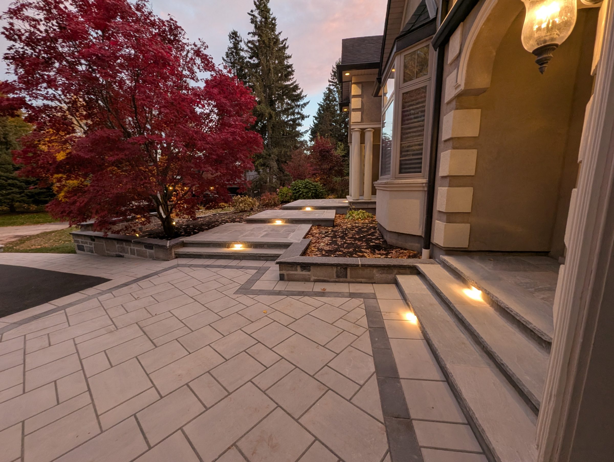 Luxury stone patio with step lighting and Japanese maple — Devine Image