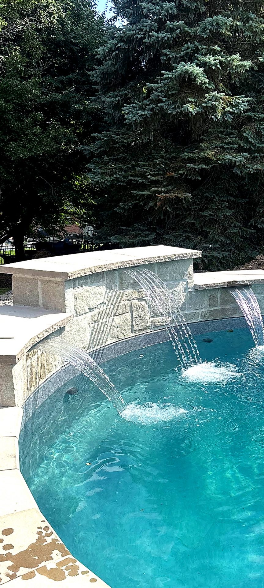 Cherry Hill backyard pool with stone waterfall feature and natural stone coping